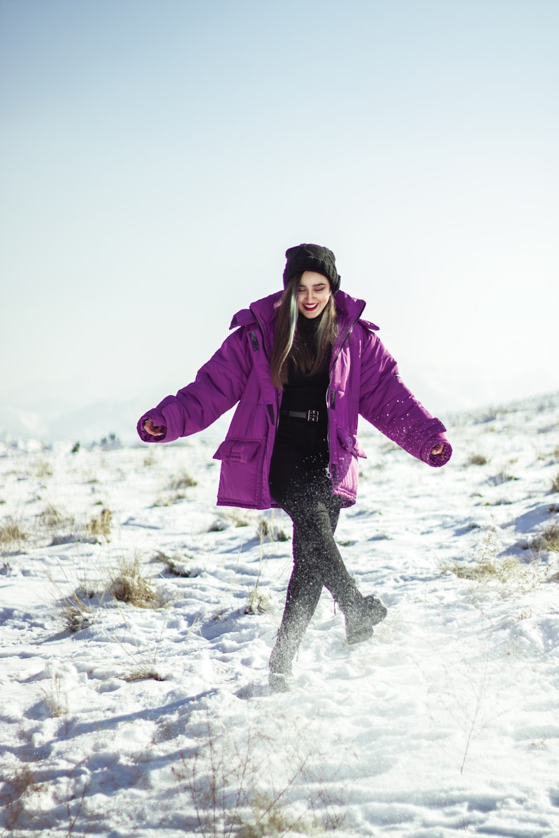 a woman in a purple coat is walking in the snow